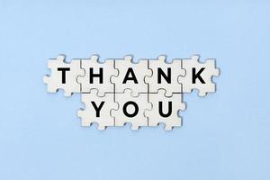 Thank you phrase on wooden puzzle isolated on blue background. Top view