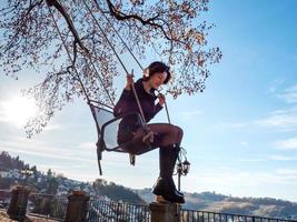 A young girl is swinging on a swing. Sunny day. photo