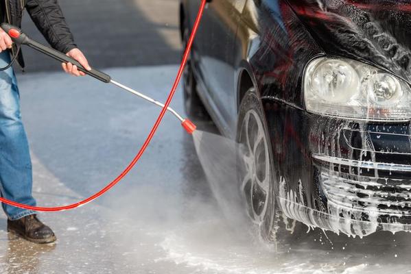 Disparo horizontal de hombre caucásico con pulverizador de alta presión con  espuma de limpieza en su coche negro en el servicio de lavado de coches al  aire libre. concepto de coche limpio