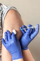 A doctor vaccinates a man against coronavirus at a clinic. Close-up. The concept of vaccination, immunization, prevention against Covid-19. photo