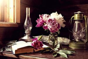 Still life of vintage items and a bouquet of peonies on a table by the window in an old village house. photo