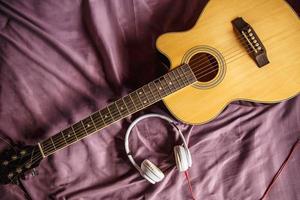 auriculares y guitarra clásica en la cama. foto