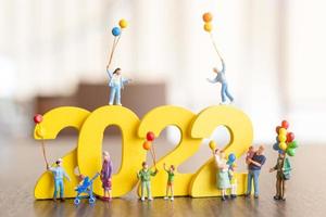 Miniature people Happy family holding balloon on white number 2022 photo