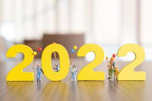 Gente en miniatura familia feliz sosteniendo globo en blanco número 2022 foto