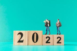 Miniature backpacker and tourist standing on wooden block number 2022 photo