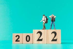 Miniature backpacker and tourist standing on wooden block number 2022 photo