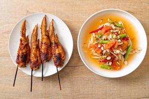 Papaya spicy salad with grilled chicken - Thai traditional street food style photo