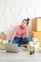 Asian woman business owner working at home with packing box on the workplace - online shopping SME entrepreneur or freelance working concept