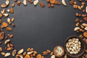 Pistachios, walnuts, pecans, and other nuts arranged on frame with black background
