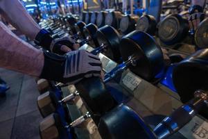 Hombres sosteniendo mancuernas en los estantes del gimnasio para hacer ejercicio foto