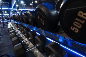 mancuernas colocadas en estantes en el gimnasio para hacer ejercicio. foto