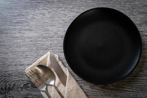 Empty plate or dish with knife, fork, and spoon on wood tile background photo