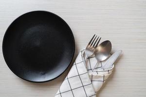 Empty plate or dish with knife, fork, and spoon on wood tile background photo