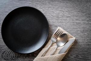 Empty plate or dish with knife, fork, and spoon on wood tile background photo