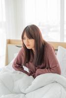 Beautiful Asian woman with stomachache and sleeping on bed photo