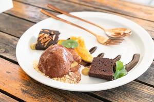 Chocolate ice-cream with chocolate brownie and caramel banana on white plate photo