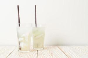 Coconut water or coconut juice in glass with ice cubes photo