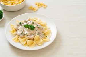 Pasta farfalle con salsa de crema blanca de champiñones - estilo de comida italiana foto