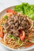 Instant noodle spicy salad with pork on white plate - Asian food style photo