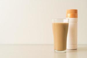 Vaso de café con leche con botellas de café listas para beber en la mesa foto
