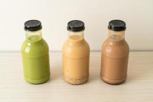 Matcha green tea latte, chocolate and milk tea with pudding jelly in glass bottle on the table photo
