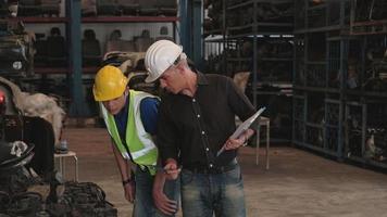 Caucasian Owner and Asian Worker. Two men checking engine parts in a warehouse. With both of them wearing helmets during working time, most of the products are machines In the automobile industry. video