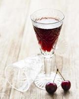 Cherry liqueur in a glass and fresh fruits