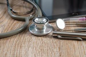 Stethoscope with syringe and dental tools on wooden table background photo