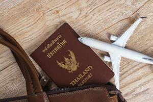 Bolso de cuero y modelo de avión pequeño sobre fondo de tablero de madera foto