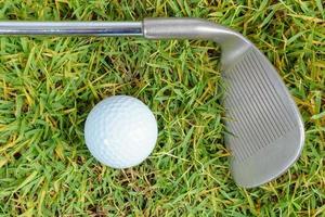 Golf clubs and golf ball on green grass background photo