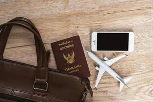 Leather bag and Small plane model on wooden board background