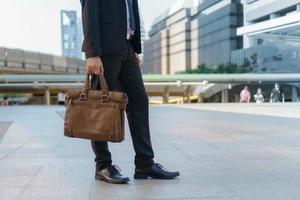 empresario caminando en la ciudad y sosteniendo maletín foto