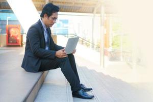 Businessman sitting on the footsteps with laptop photo