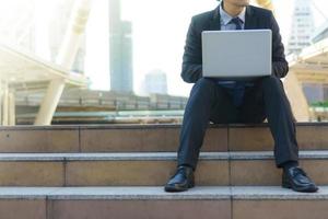 Businessman sitting on the footsteps with laptop photo