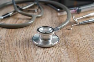 Stethoscope with syringe on wooden table background photo