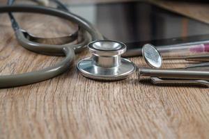 Stethoscope with syringe on wooden table background photo