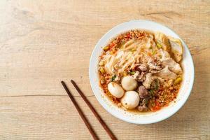 Noodles with pork and meatballs in spicy soup or Tom yum noodles in Asian style photo