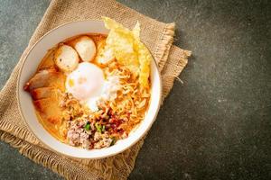 Instant noodles with pork and meatballs in spicy soup or Tom Yum Noodles in Asian style photo