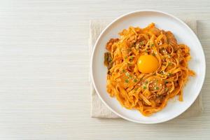 Stir-fried udon noodles with kimchi and pork - Korean food style photo