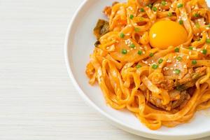 Stir-fried udon noodles with kimchi and pork - Korean food style photo