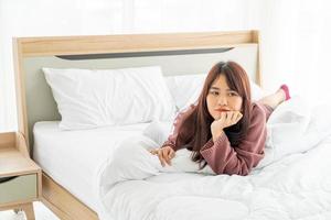 Beautiful Asian woman lying on bed in the morning photo