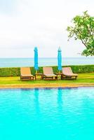 Chair pool and umbrella around swimming pool with ocean sea background photo