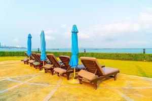 Chair pool and umbrella around swimming pool with ocean sea background photo