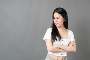 Young Asian woman with sulk face in white shirt on grey background