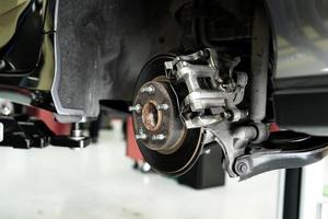 Disc car close up - mechanic unscrewing automobile parts while working under a lifted auto photo