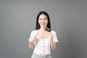 Mujer asiática con cara feliz y presentando tarjeta de crédito en mano mostrando confianza y seguridad para realizar el pago foto