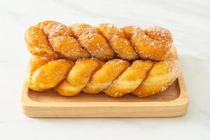 Sugar doughnut in spiral shape on wooden plate photo