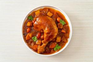 Homemade chicken stew with tomatoes, onions, carrot and potatoes on plate photo