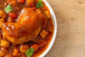 Homemade chicken stew with tomatoes, onions, carrot and potatoes on plate photo