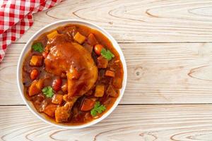 Guiso de pollo casero con tomates, cebollas, zanahorias y patatas en la placa foto